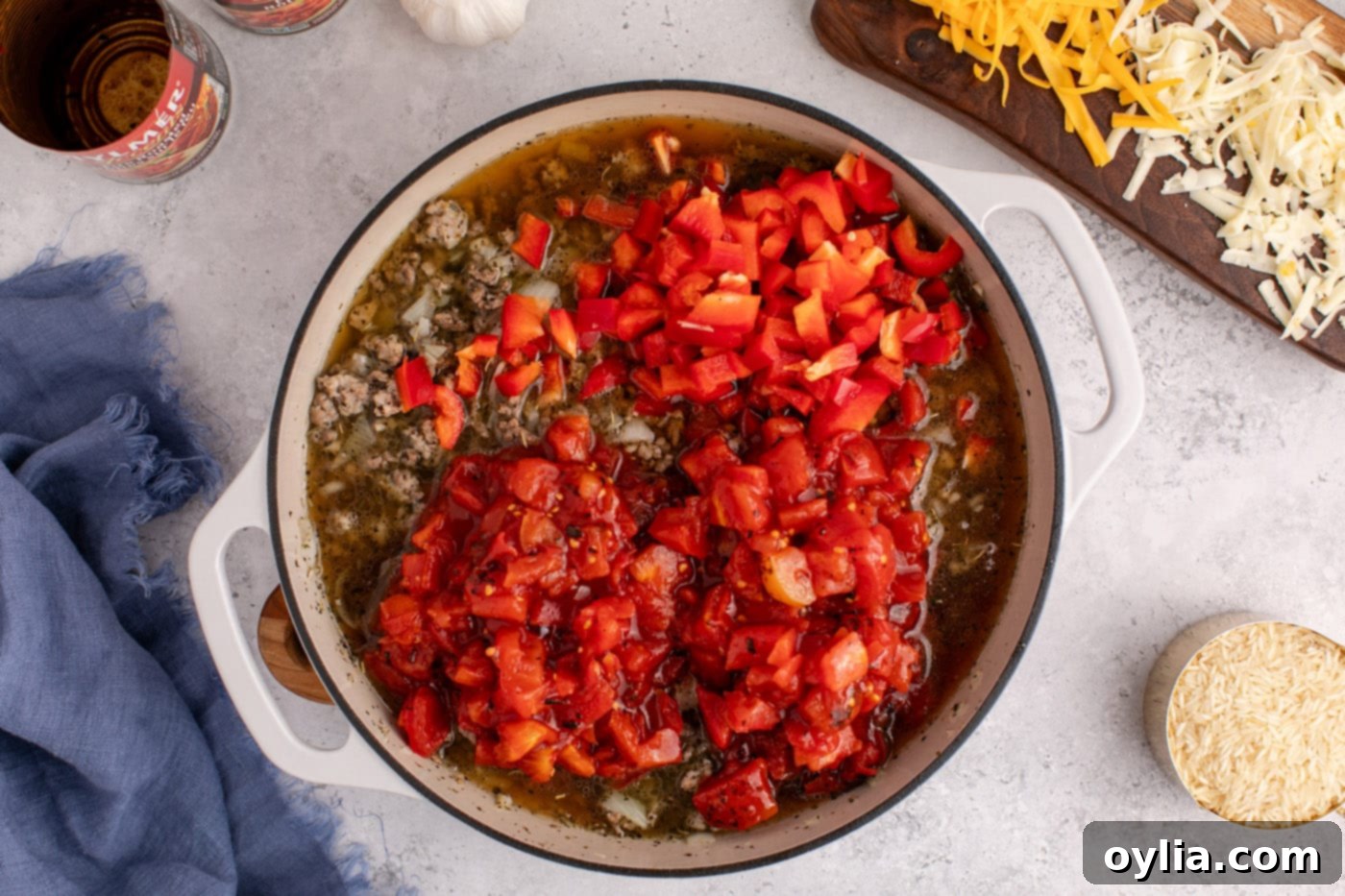 Fire-roasted tomatoes and chopped bell peppers added to the beef and sausage mixture, creating a rich base for the casserole.