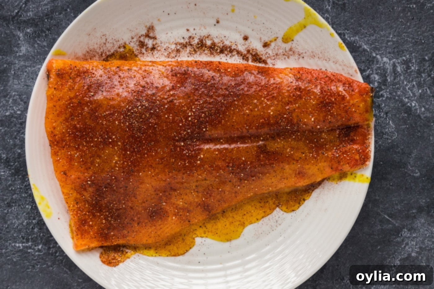 Seasoned salmon fillet on a plate, ready for the smoker