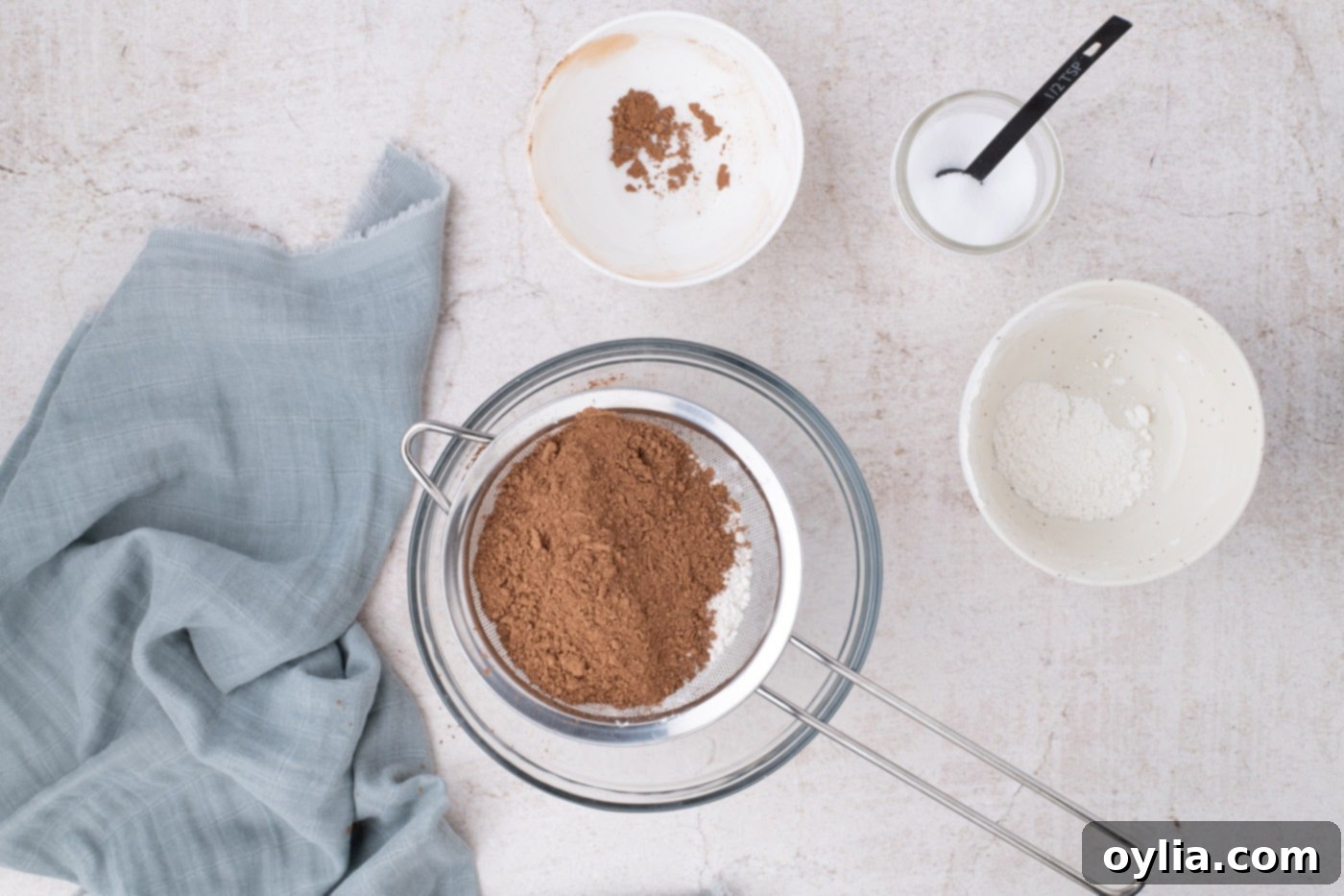 Sifting all-purpose flour and unsweetened cocoa powder into a mixing bowl to remove clumps and aerate.