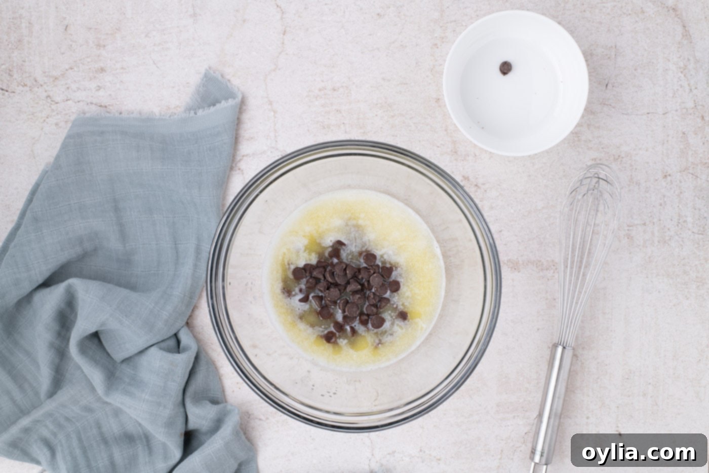 Semi-sweet chocolate chips in a bowl with melted butter, sitting to soften before stirring.