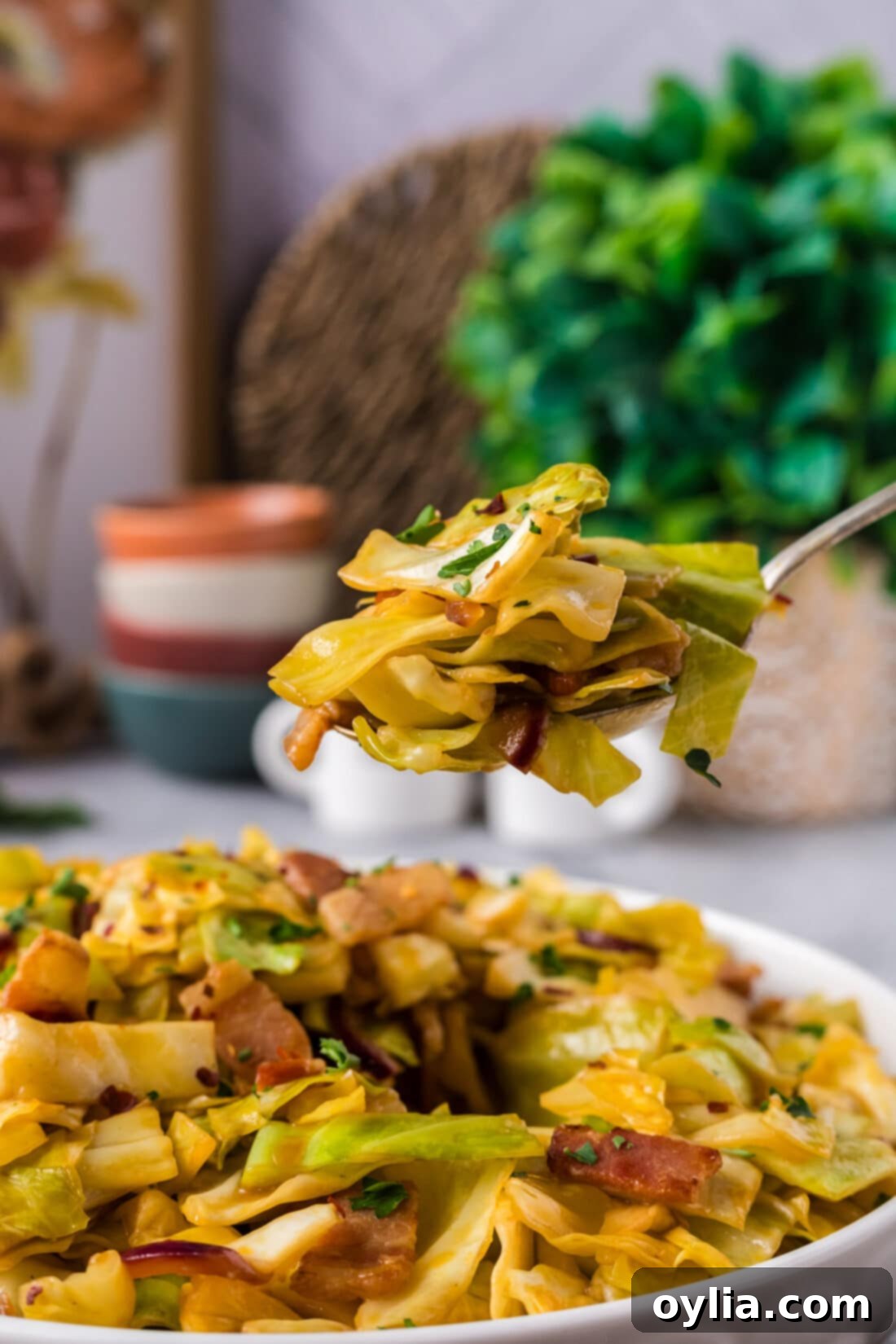 Spoonful of Spicy Fried Cabbage held above a bowl of Spicy Fried Cabbage, showcasing its delicious appeal.