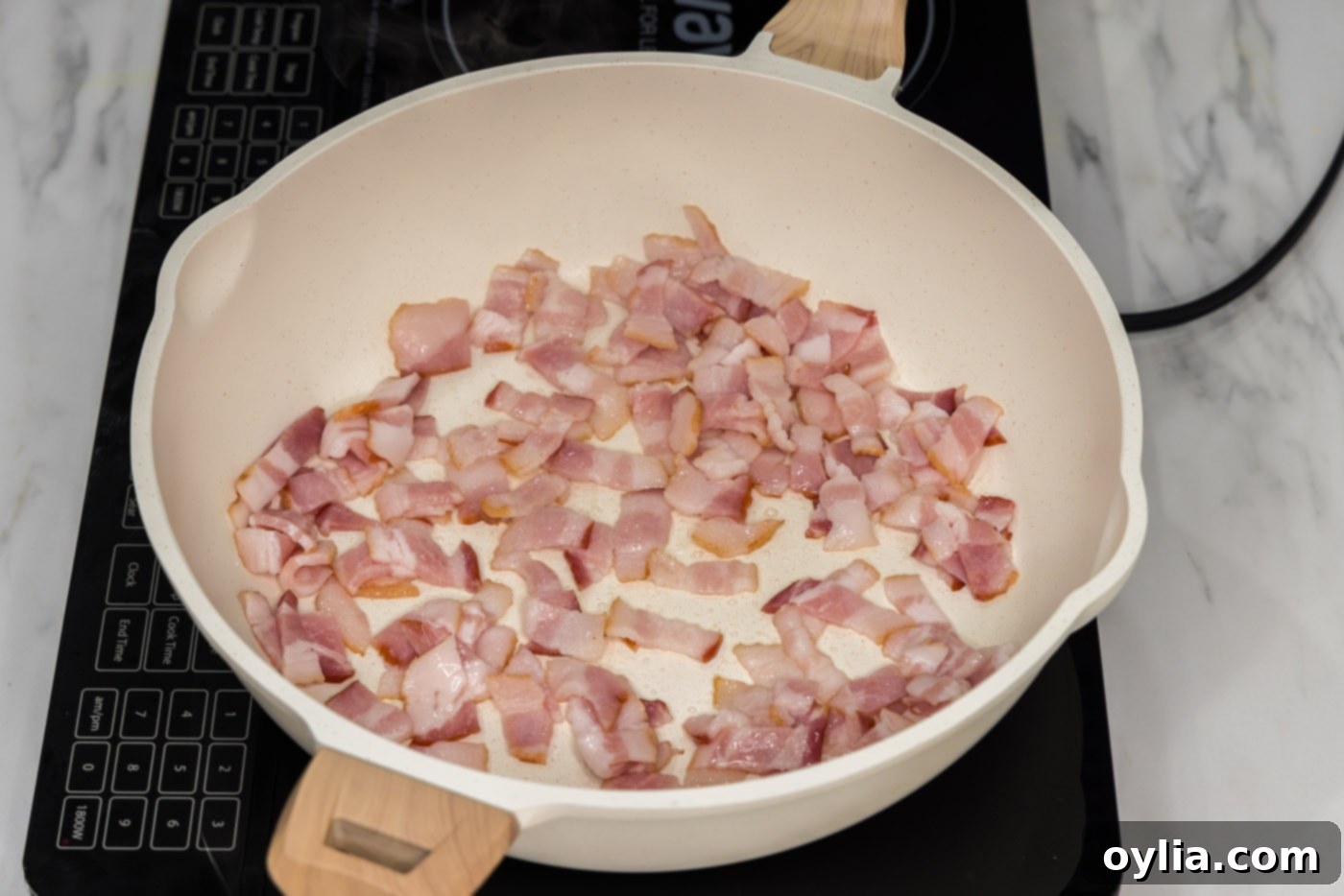 chopped bacon in a skillet, beginning to render fat.