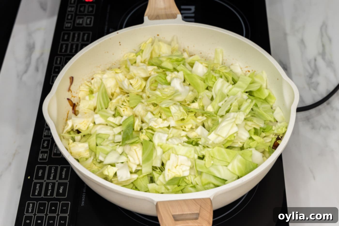 chopped cabbage added to skillet, ready to be incorporated into the sauce.