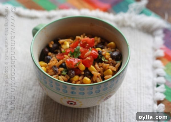 A close up photo of Spanish rice with black beans and corn in a teal and white serving bowl, showing the vibrant colors and textures.