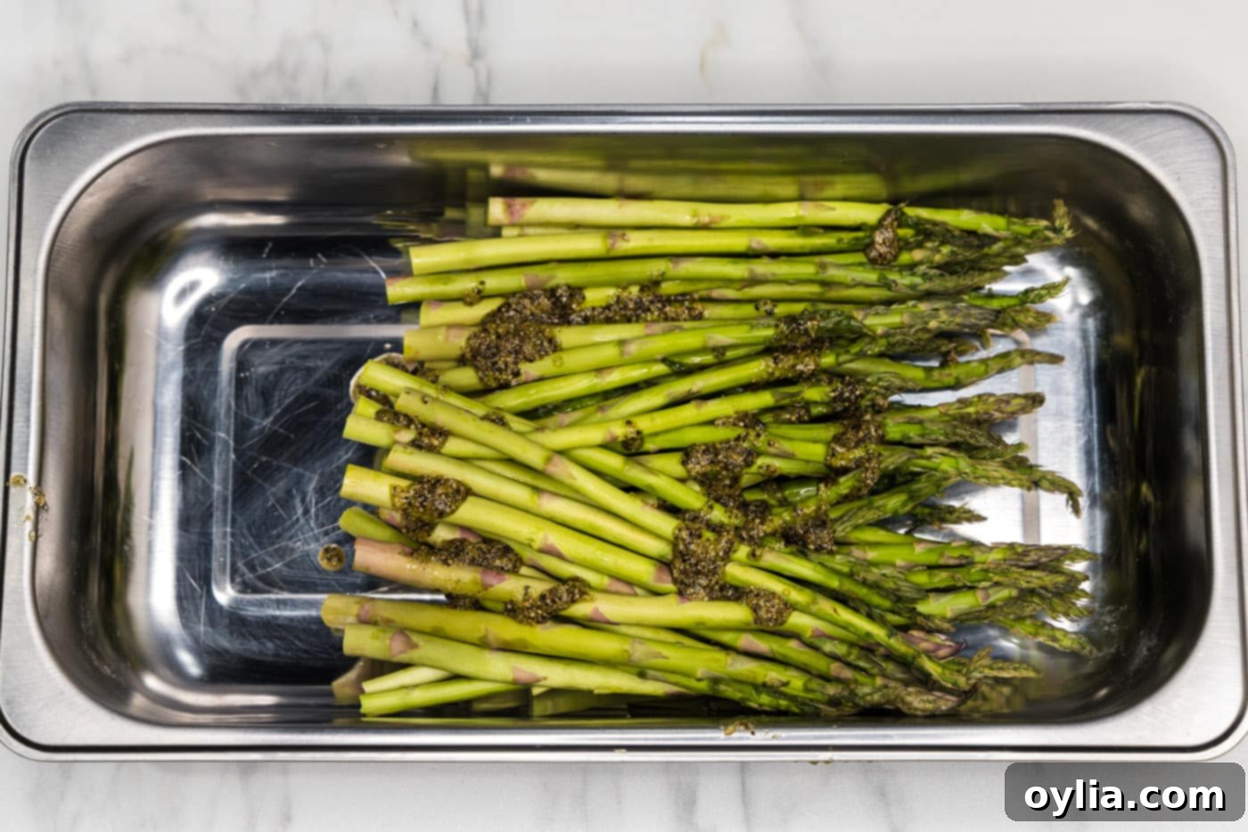 olive oil and seasonings on top of asparagus spears