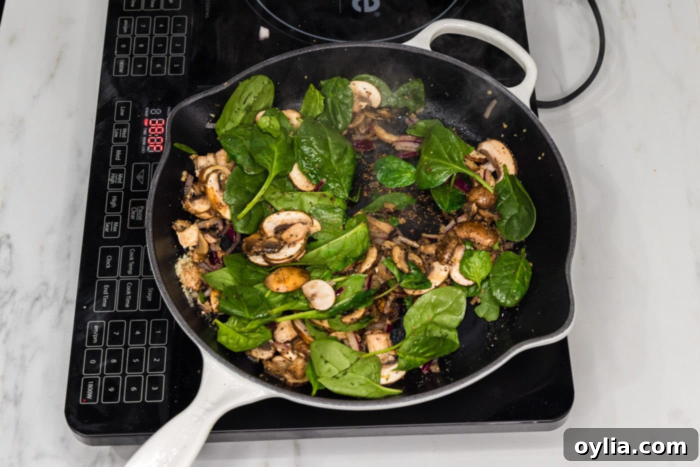 fresh spinach leaves added to skillet with mushrooms and onion