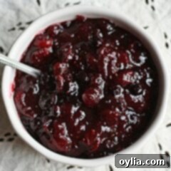 Bursting Berry Cranberry Sauce 6 An overhead photo of whole berry cranberry sauce in a white bowl with a spoon.