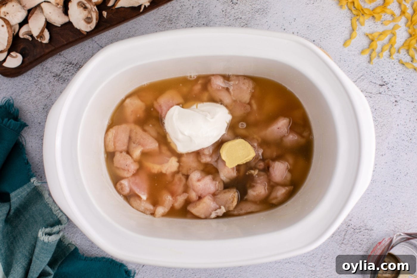 Sour cream, chicken stock, Dijon mustard, and Worcestershire sauce added to the crockpot with seasoned chicken.