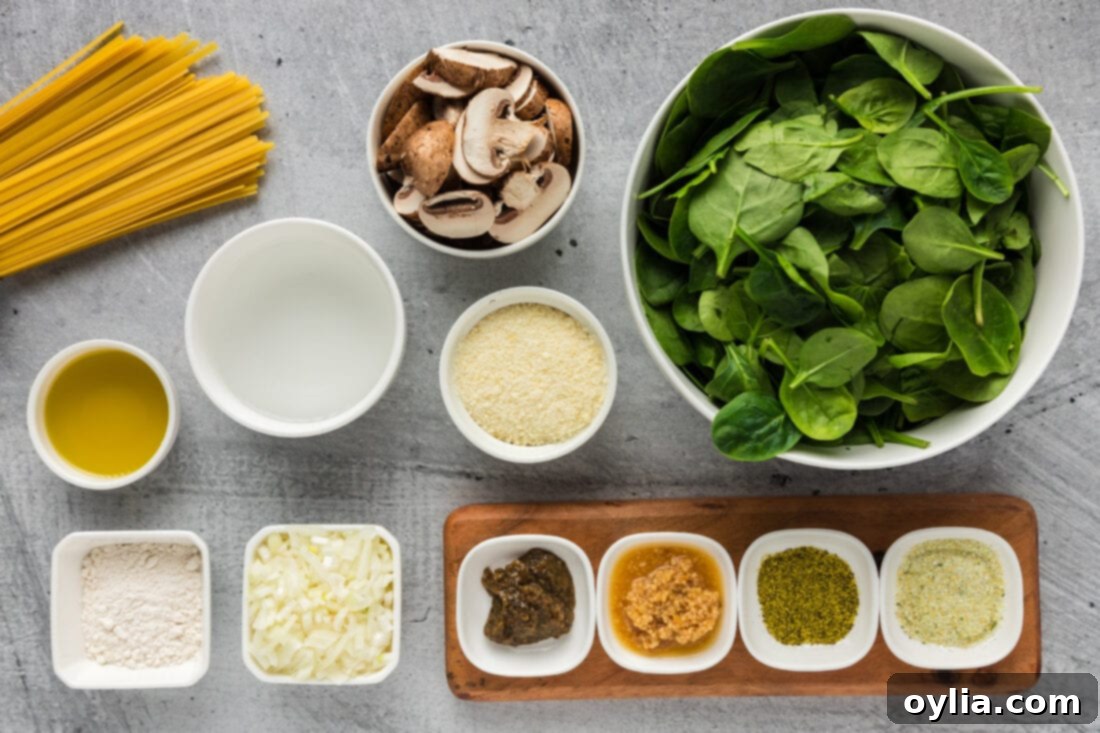 Fresh Spinach Fettuccine 4 Various fresh ingredients laid out for Spinach Fettuccine including vibrant spinach, sliced mushrooms, minced garlic, diced onion, and uncooked fettuccine pasta
