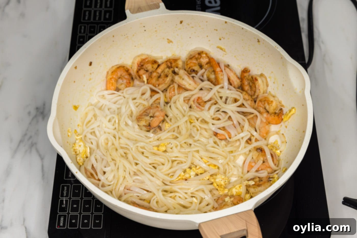 cooked rice noodles added to skillet with shrimp and egg