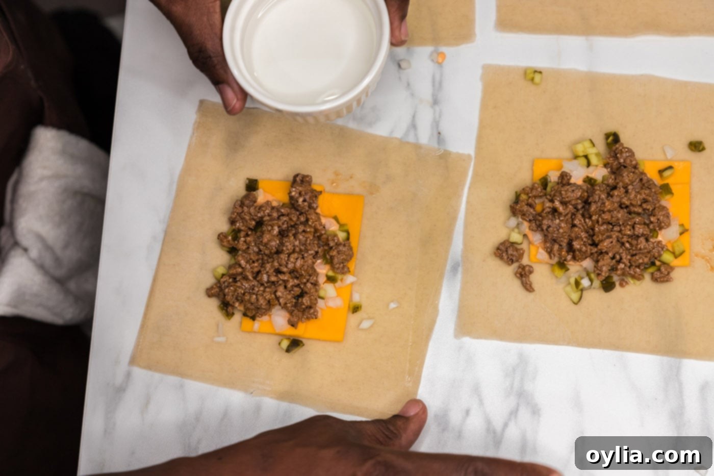 A finger moistening the edges of an egg roll wrapper with water to seal it.
