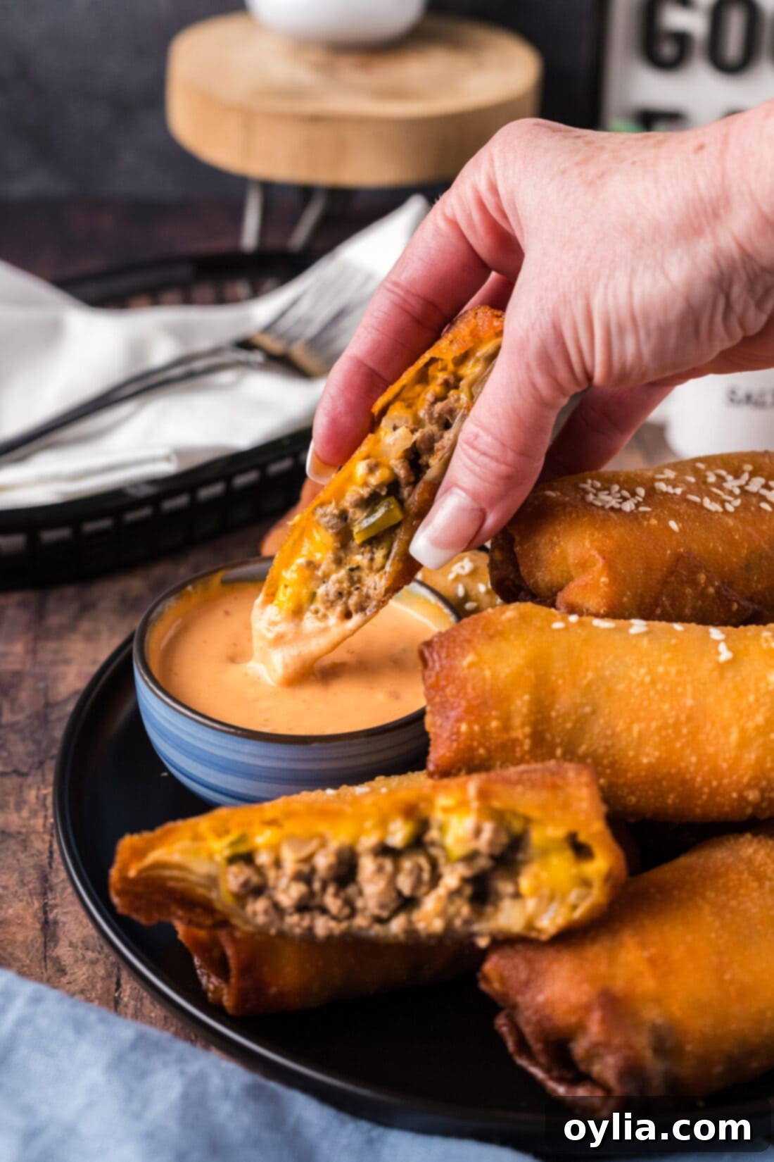 A Big Mac Egg Roll, cut in half, being dipped into a bowl of creamy Thousand Island dressing.