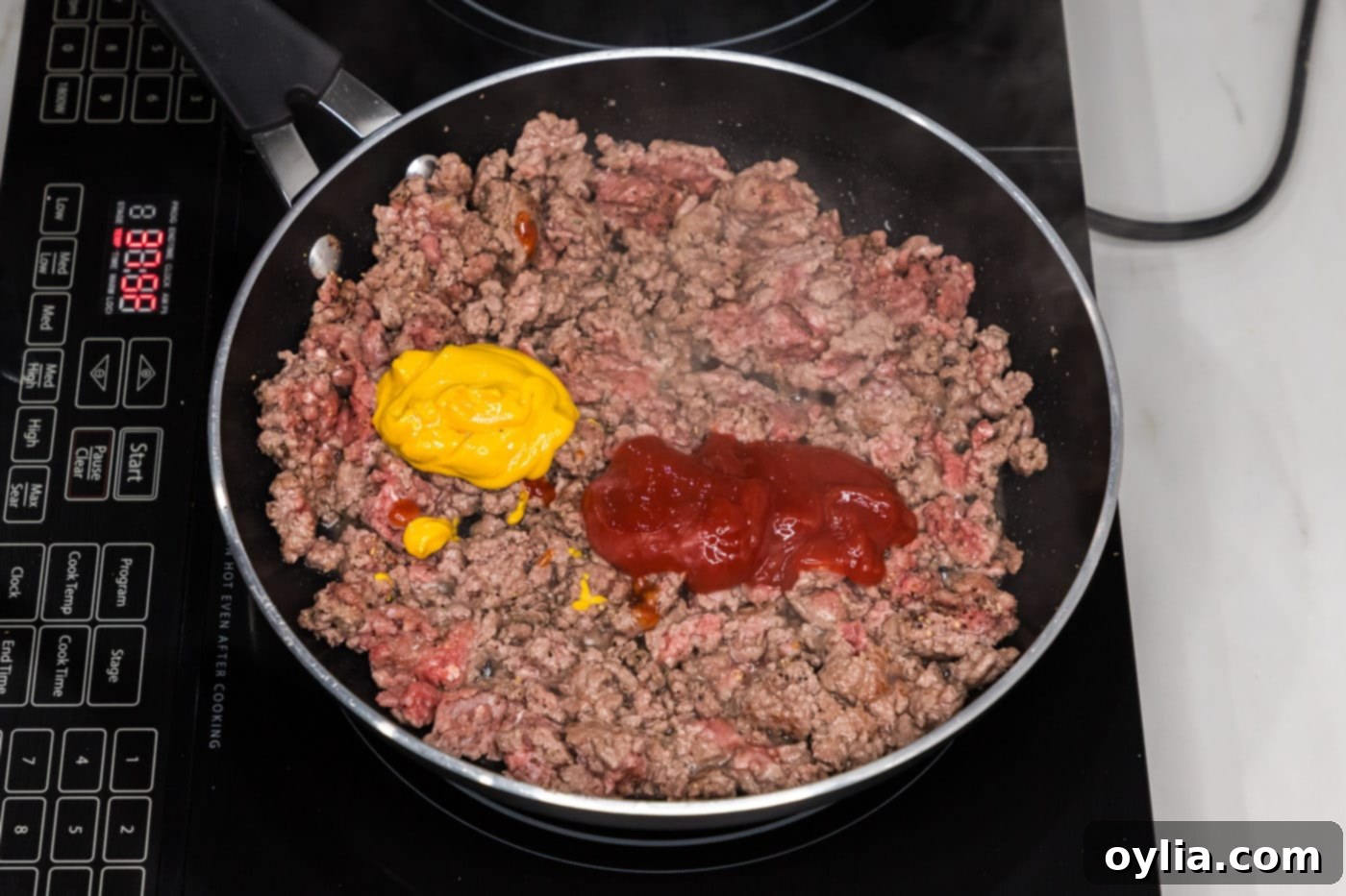 mustard and ketchup added to ground beef in skillet