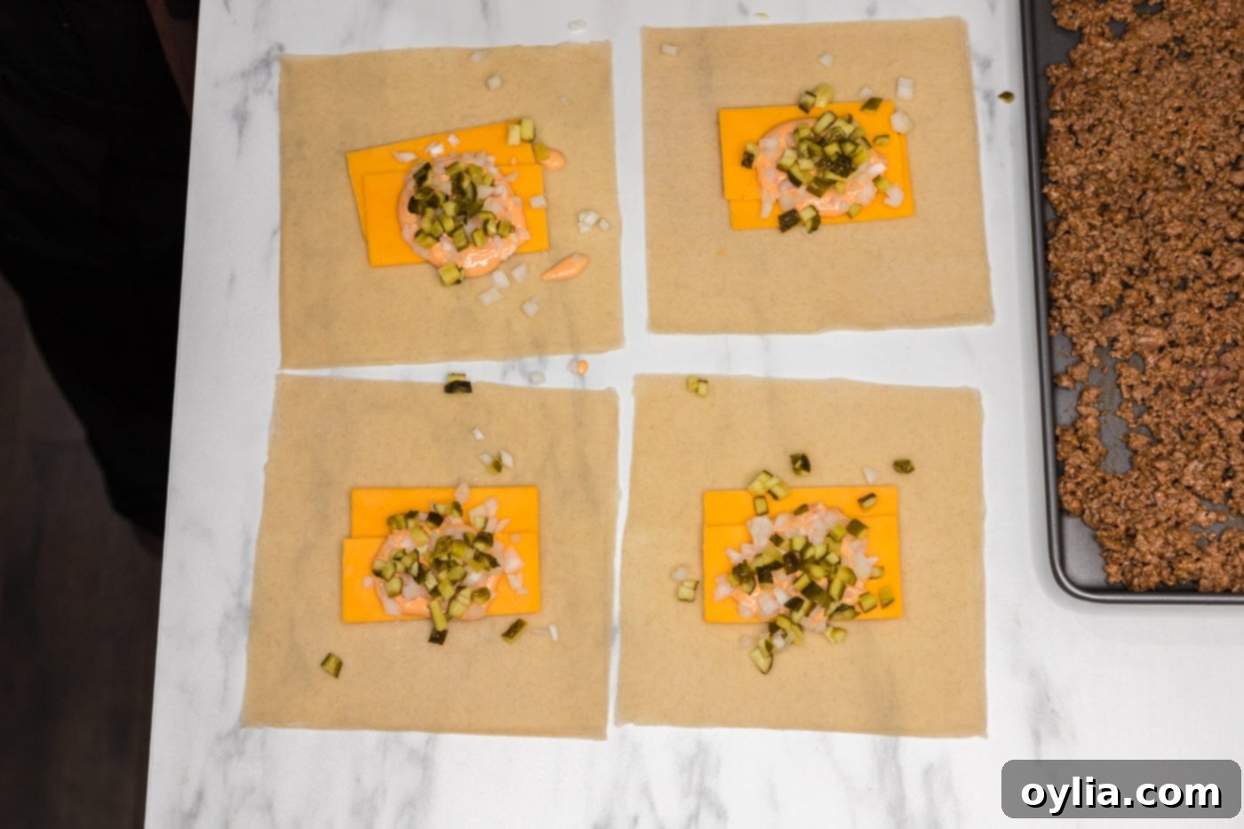 egg roll wrappers with cheddar cheese, onion, and pickles as the base of the filling