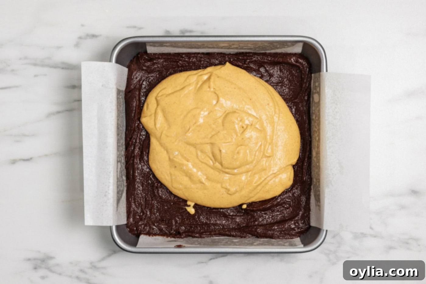 Spiced Pumpkin Swirl Cheesecake Brownies 12 Pumpkin cheesecake batter poured over the brownie layer in a baking pan