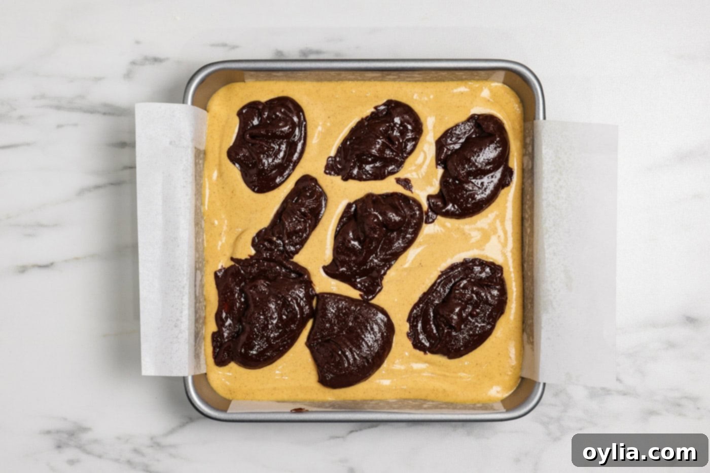 Spiced Pumpkin Swirl Cheesecake Brownies 13 Spoonfuls of brownie batter dolloped on top of the pumpkin cheesecake layer