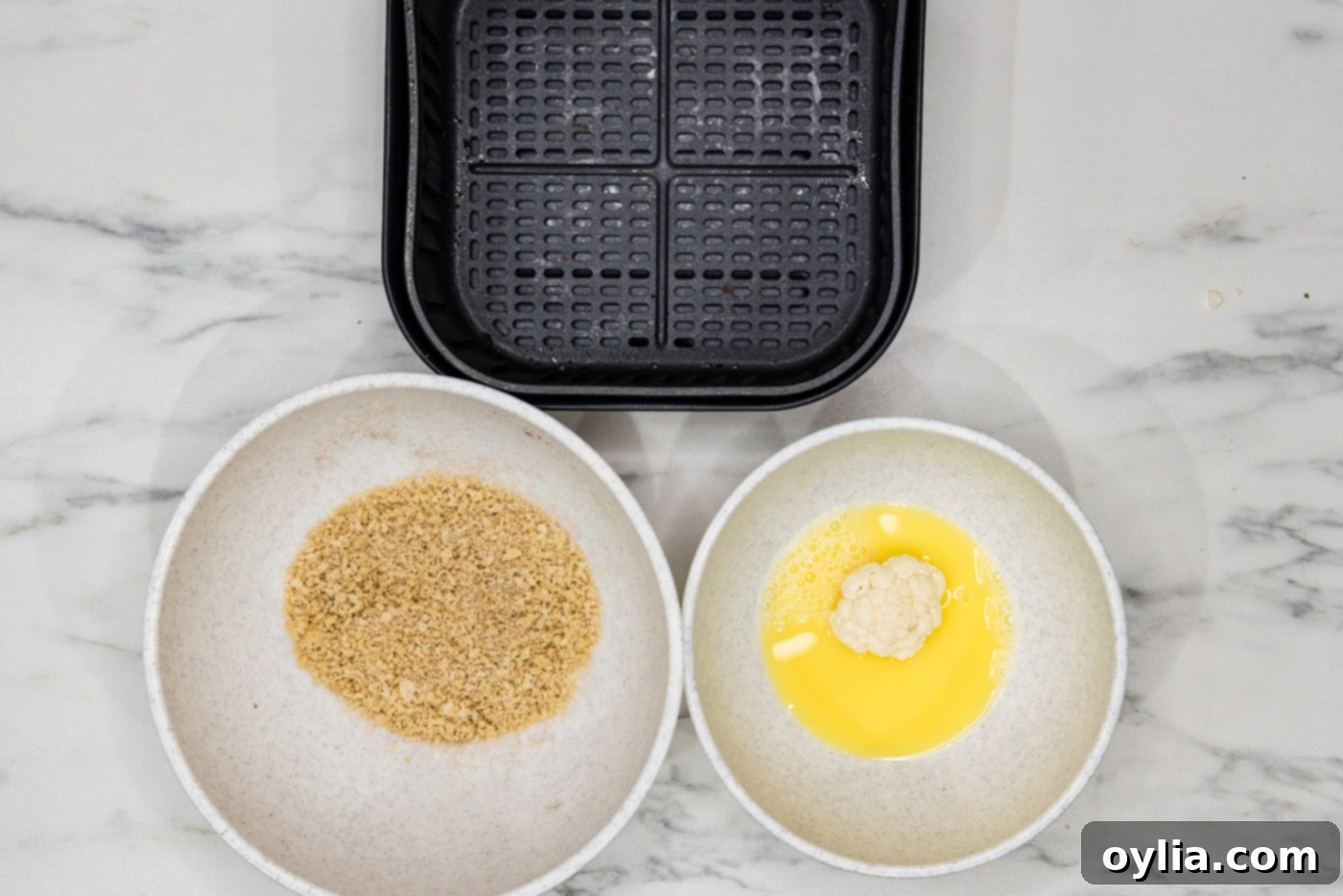 cauliflower florets in a bowl of egg and water