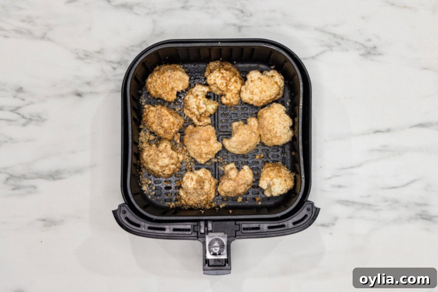 panko coated cauliflower florets in an air fryer basket