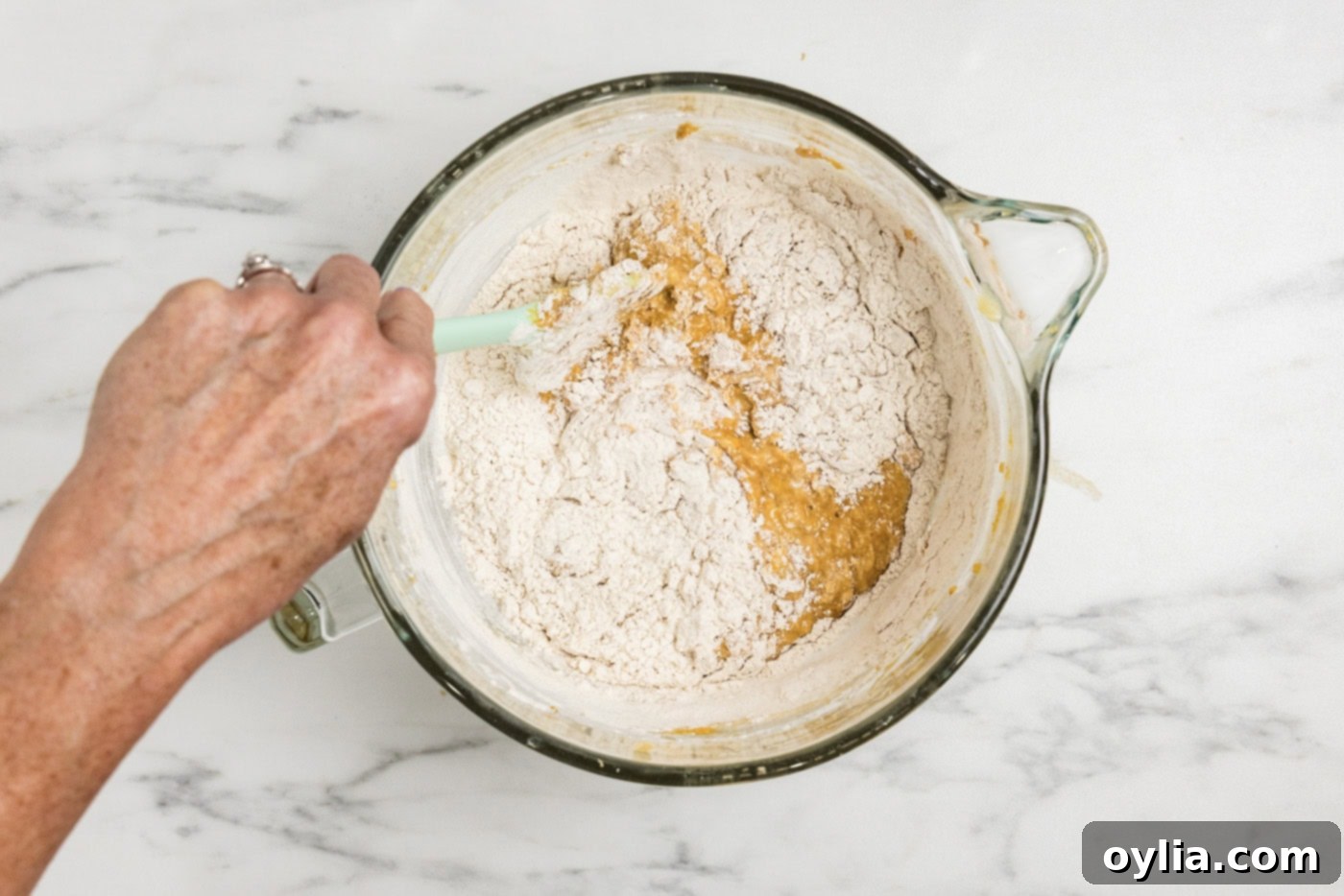 folding the rest of the flour into pumpkin batter with a rubber spatula, ensuring not to overmix