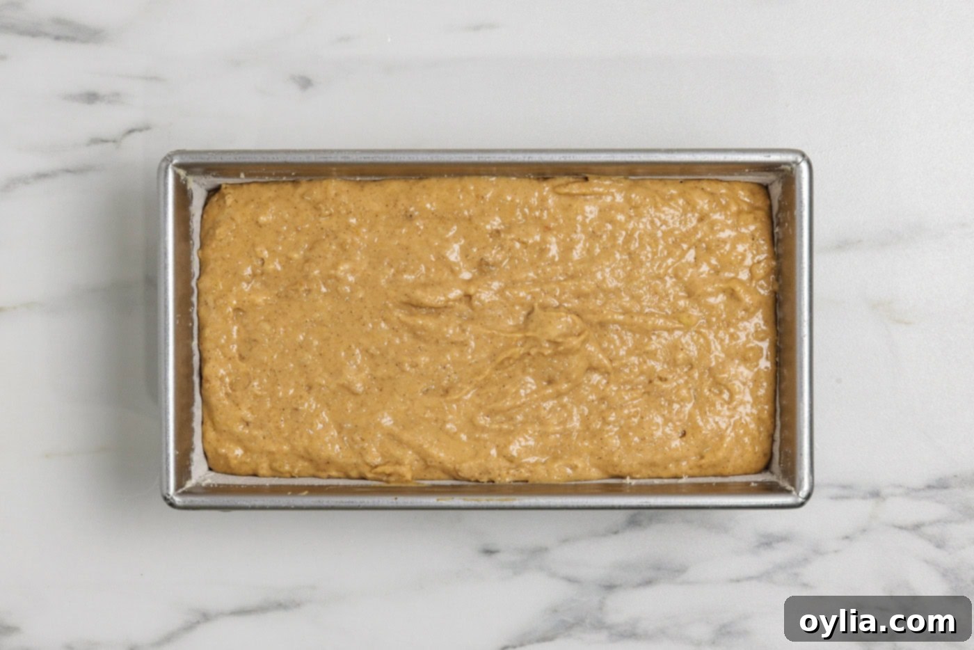 pumpkin banana bread batter in a floured loaf pan, ready for baking