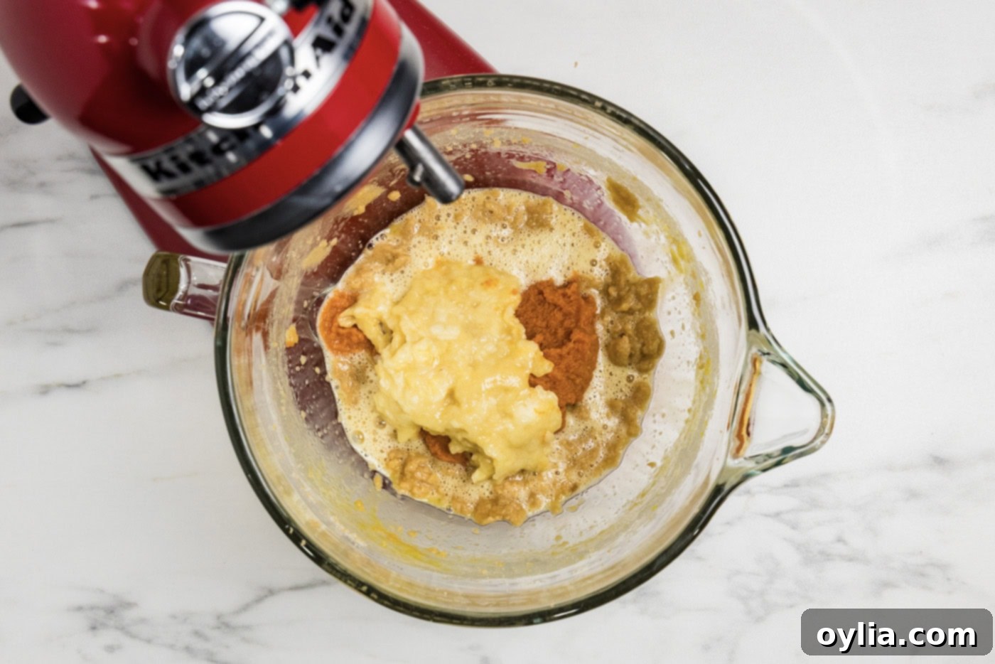 spices, pumpkin, and banana added to the wet mixture in a stand mixer bowl
