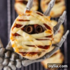 Mummy Pizza Bites 10 Close up photo of a Mini Mummy Pizza in a skeleton hand