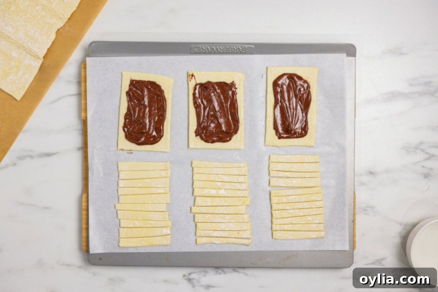 Bandaged Pastry Pockets 7 Nutella generously spread onto puff pastry rectangles, carefully leaving a clean border around the edges for effective sealing.