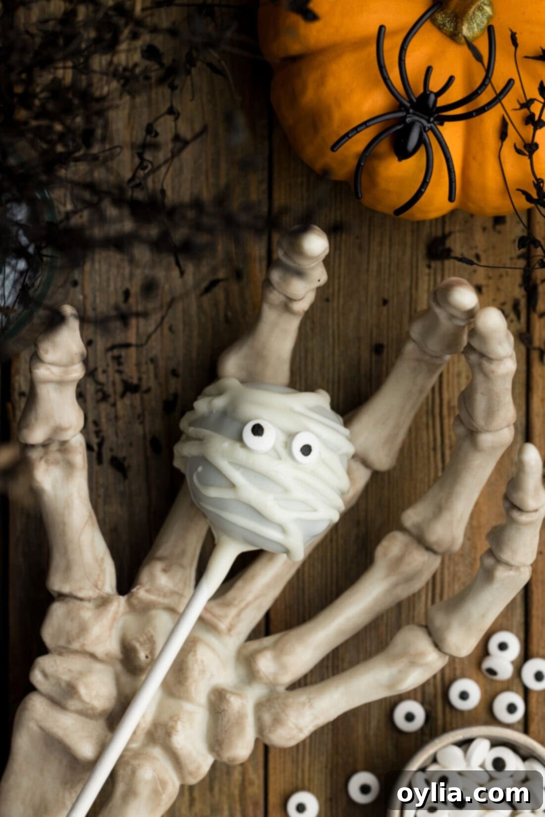A Mummy Pop resting in a skeleton hand, creating a spooky Halloween vibe