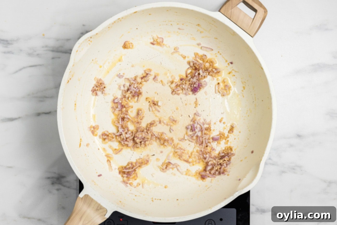 Minced garlic and diced shallots are gently sautéing in melted butter in a skillet until soft and aromatic.