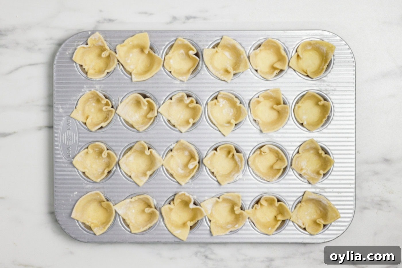puff pastry squares tucked inside cavities on a mini muffin tin