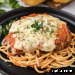 Close up photo of Veal Parmesan plated on top of spaghetti