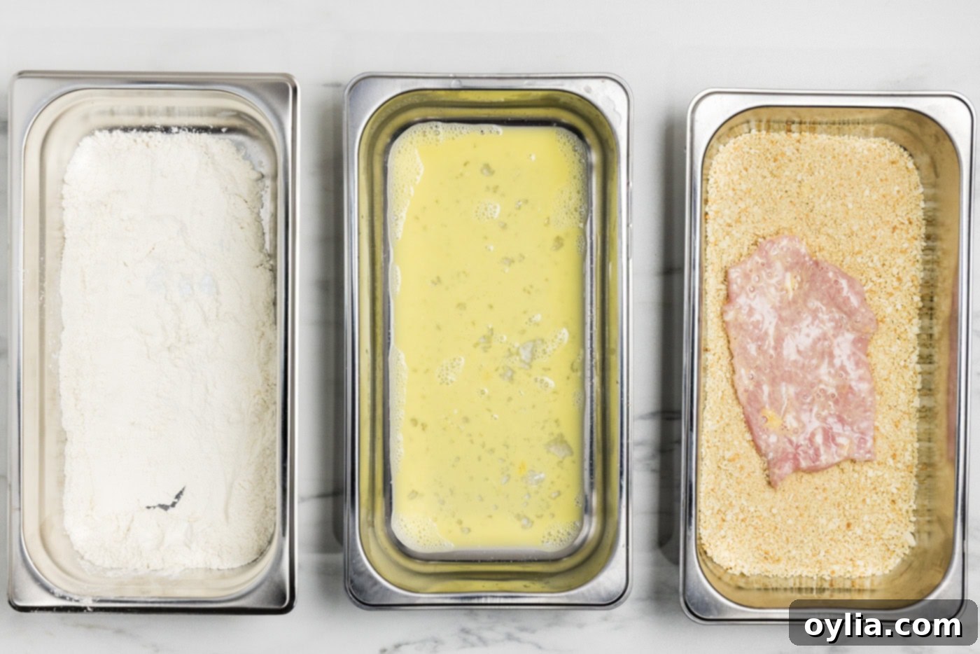 Dredged veal cutlet in breading tray with panko bread crumbs