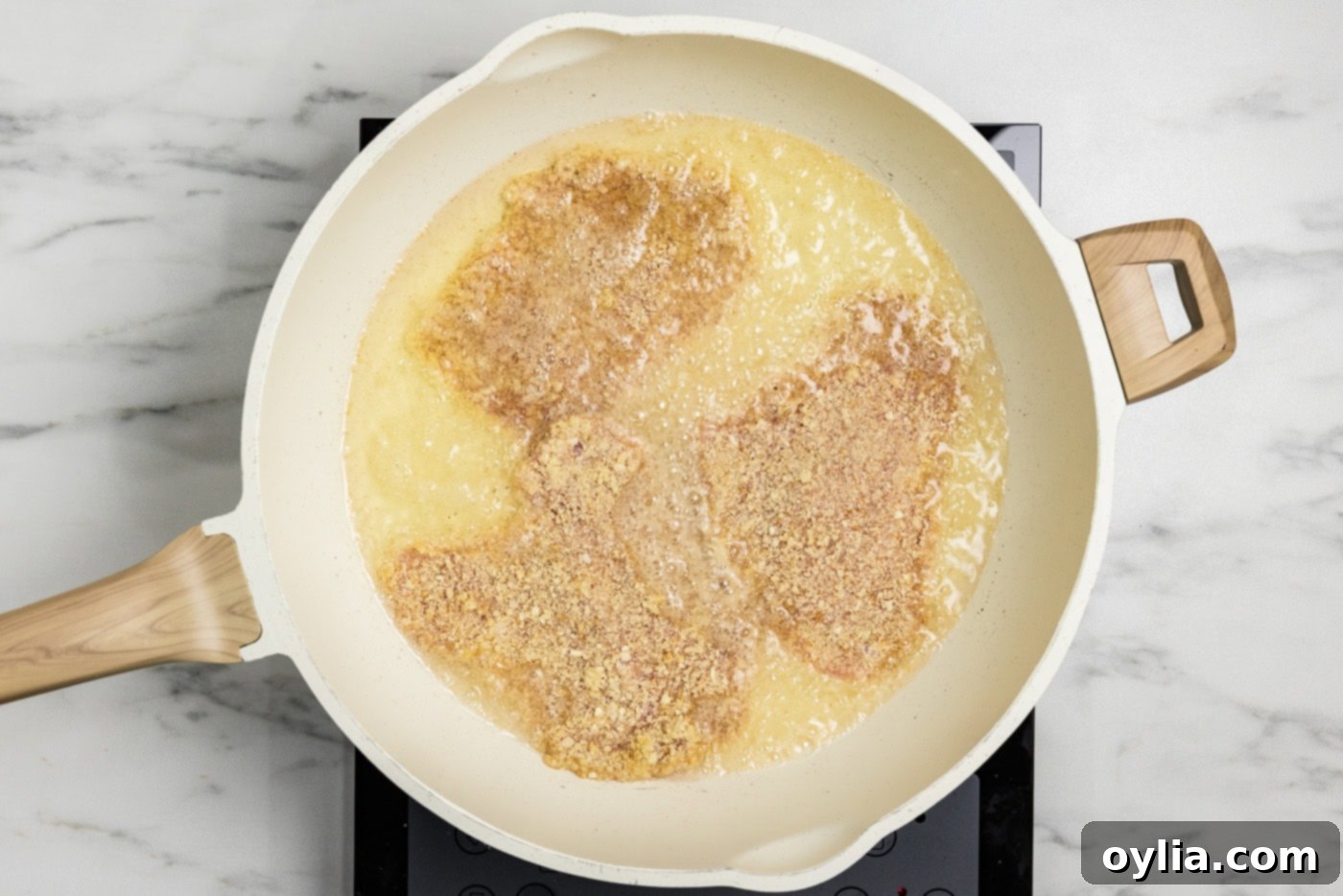 Frying panko breaded veal cutlets in a skillet with oil