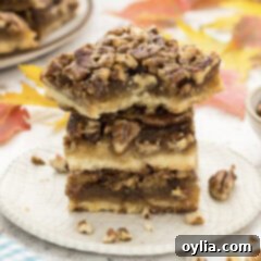 Close up photo of a stack of Pecan Pie Bars with a bite taken out of one, showing the inviting layers.