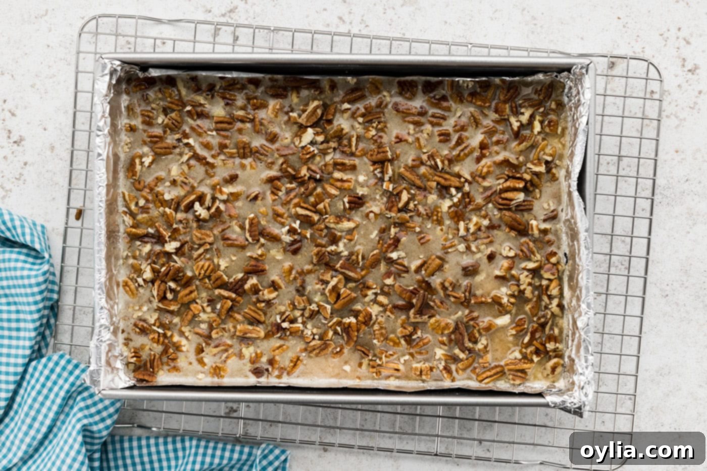 The smooth pecan pie filling poured over the shortbread crust in a baking dish, with extra pecans sprinkled on top.