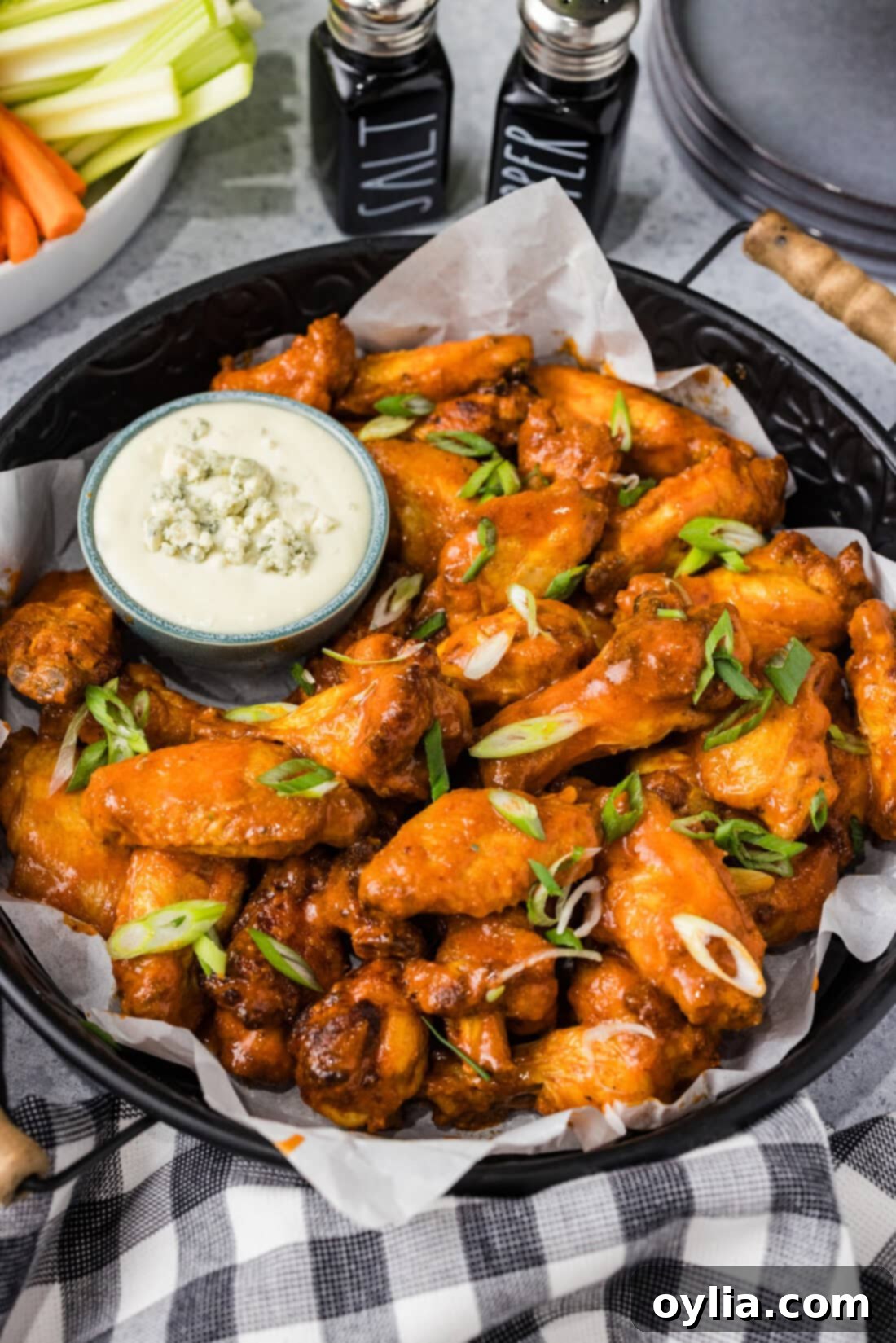 Platter of golden-brown Buffalo Chicken Wings served with a side bowl of creamy blue cheese dressing and celery sticks.