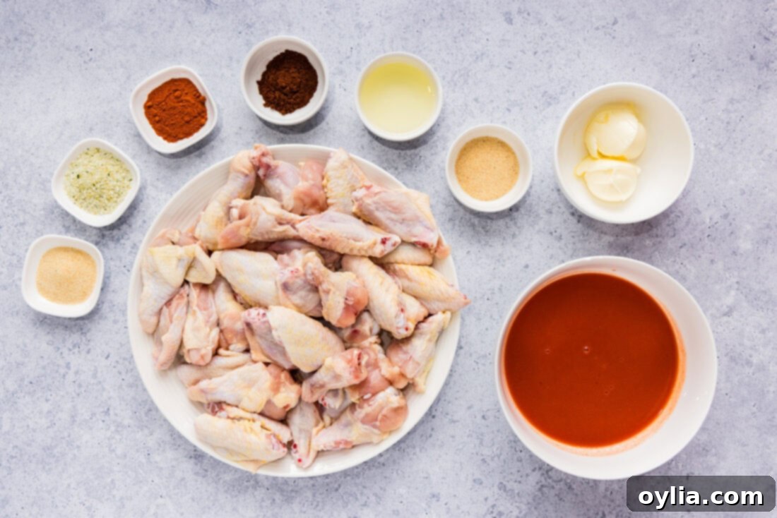 All ingredients for homemade Buffalo Chicken Wings laid out on a wooden surface, including chicken wings, spices, hot sauce, and butter.