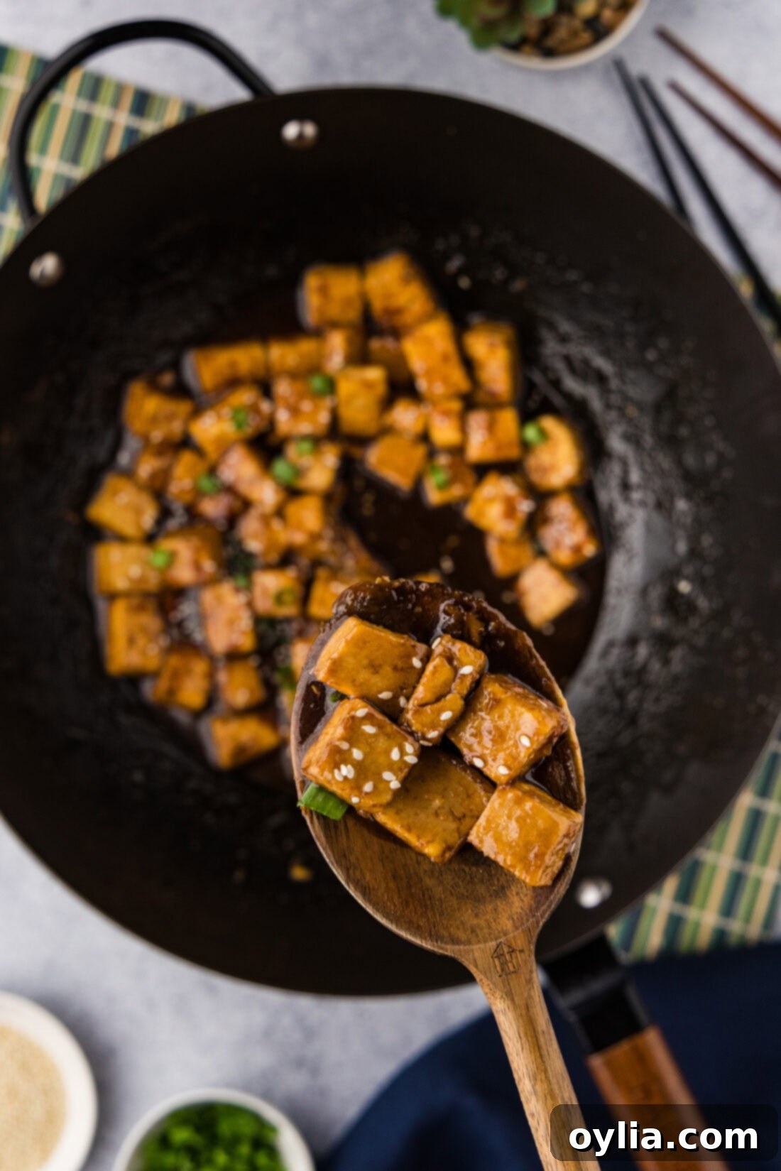Spoonful of Teriyaki Tofu held above a wok of Teriyaki Tofu