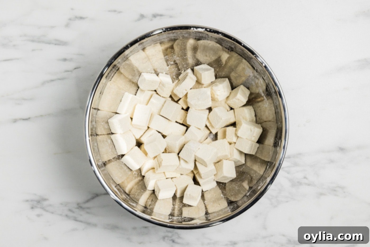 tofu cubes in a mixing bowl tossed in cornstarch