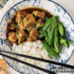 Close up photo of a bowl of Instant Pot Honey Garlic Chicken with rice and sugar snap peas