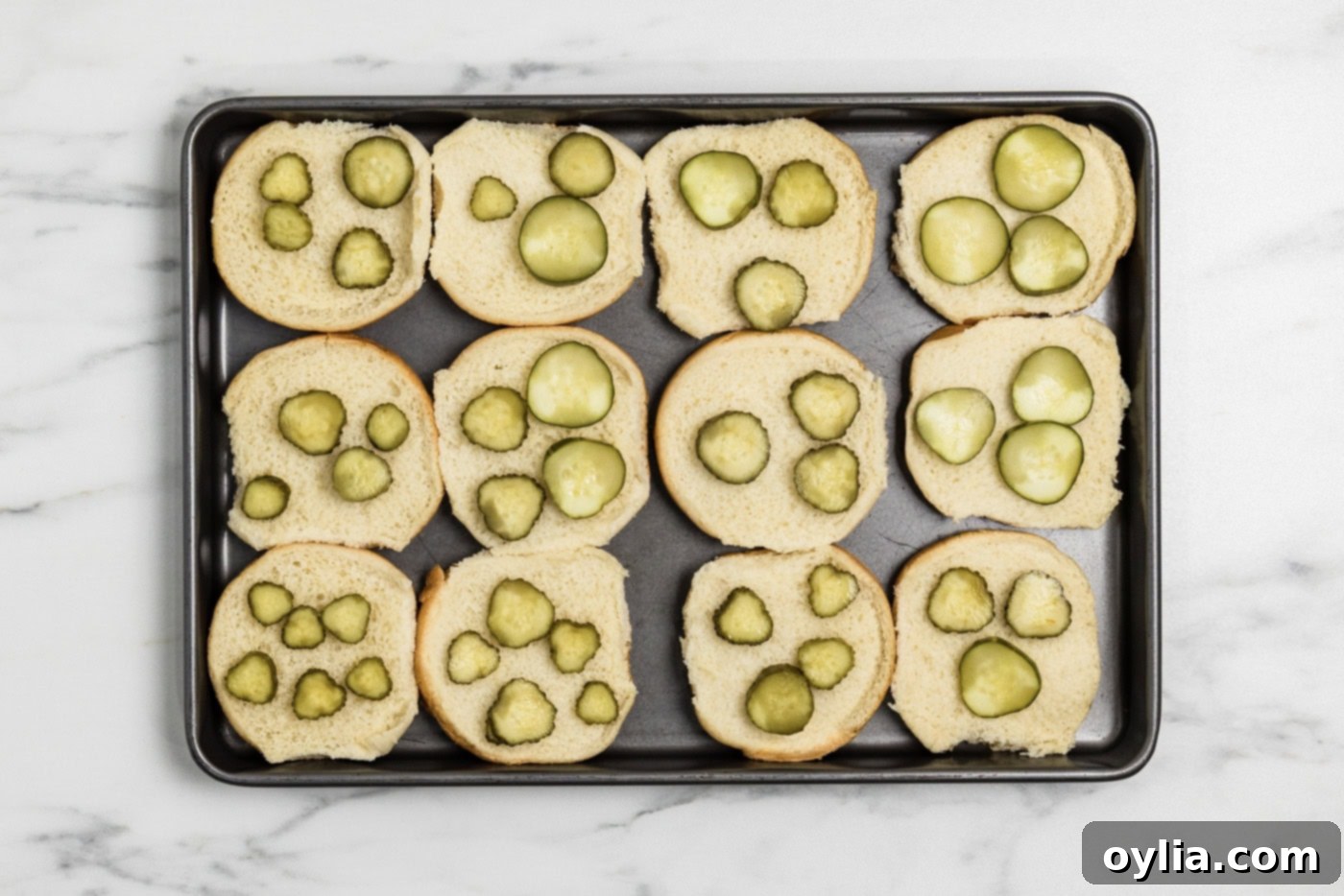 sliders buns on a baking sheet with pickles