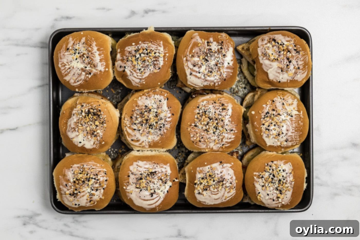 gouda chicken sliders on a baking sheet brushed with butter and sprinkled with everything bagel seasoning
