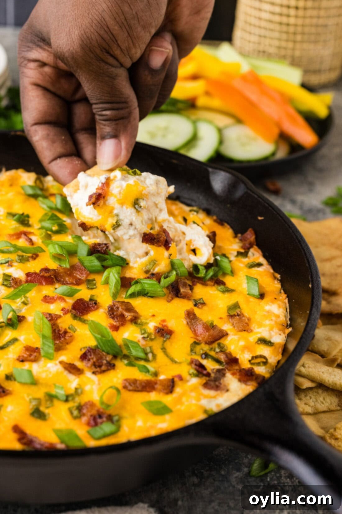 Hand scooping up Chicken Bacon Ranch Dip with a chip