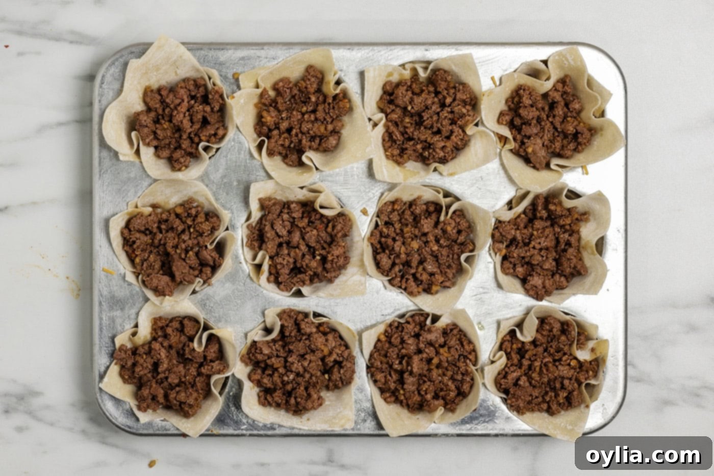 Taco meat layer overtop shredded cheese inside a wonton wrapper