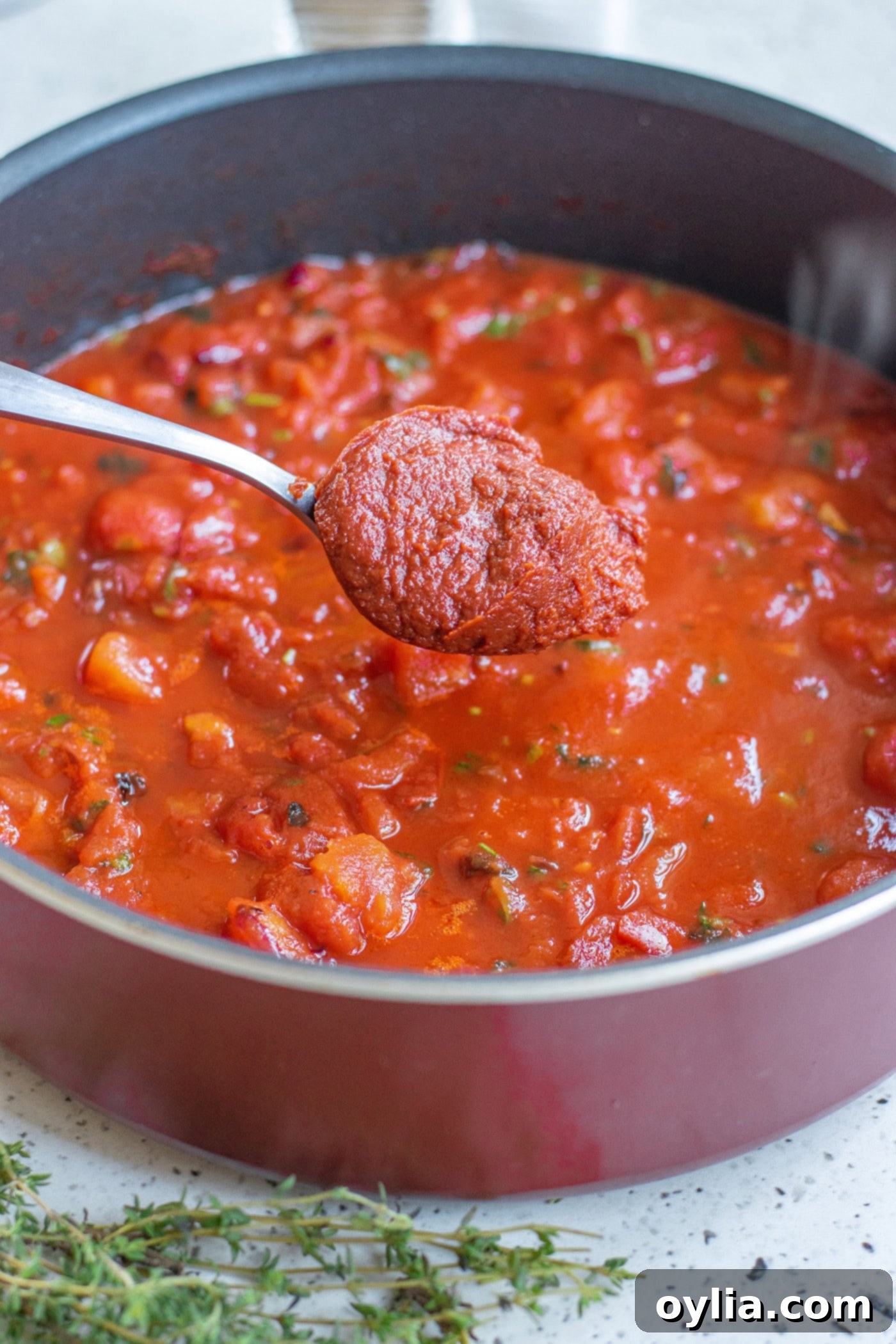 Homemade Marinara: A Taste of Italy 5 Spoonful of tomato paste being added to a pot of marinara sauce