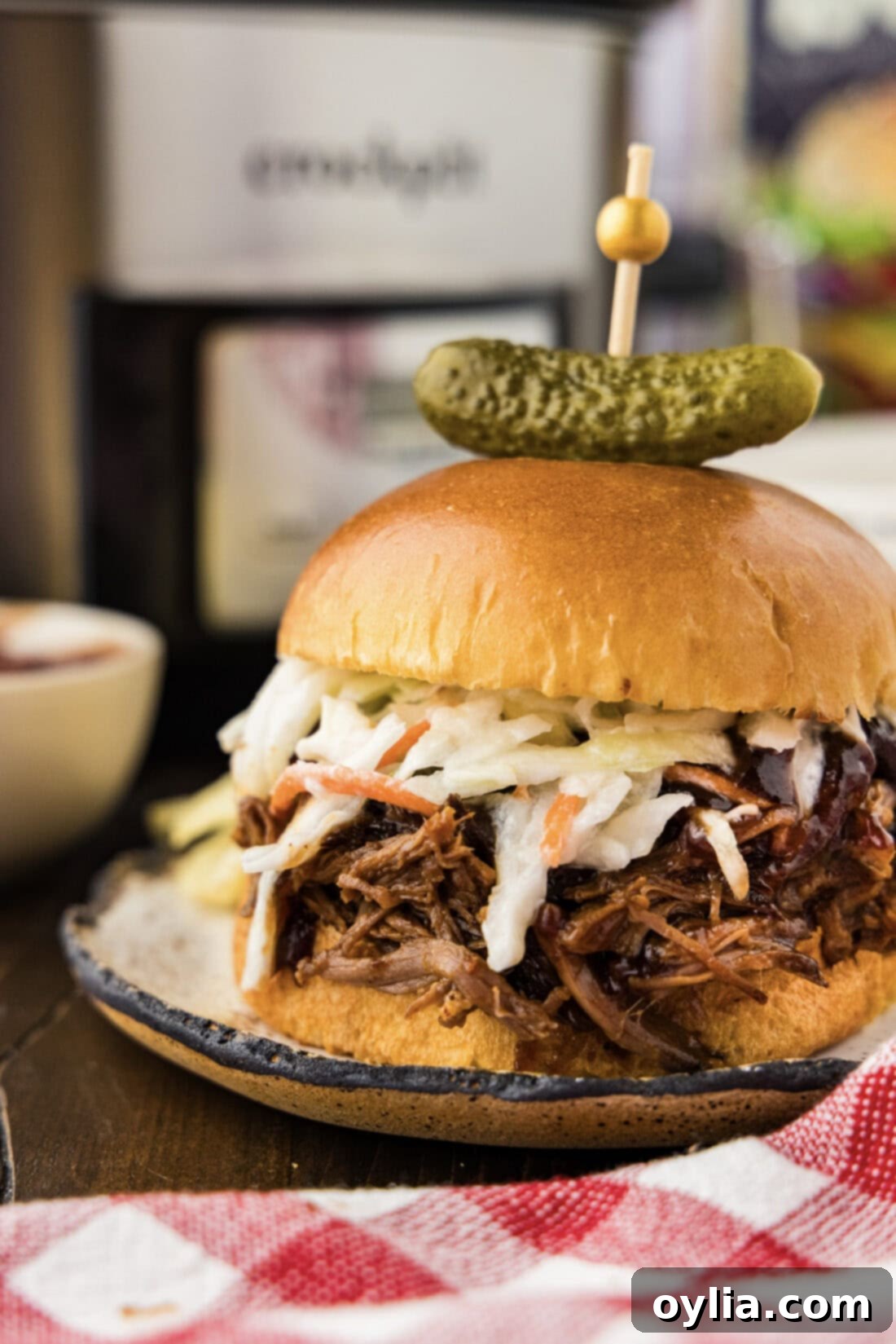 Close up photo of a Crockpot BBQ Beef Sandwich with a pickle on top