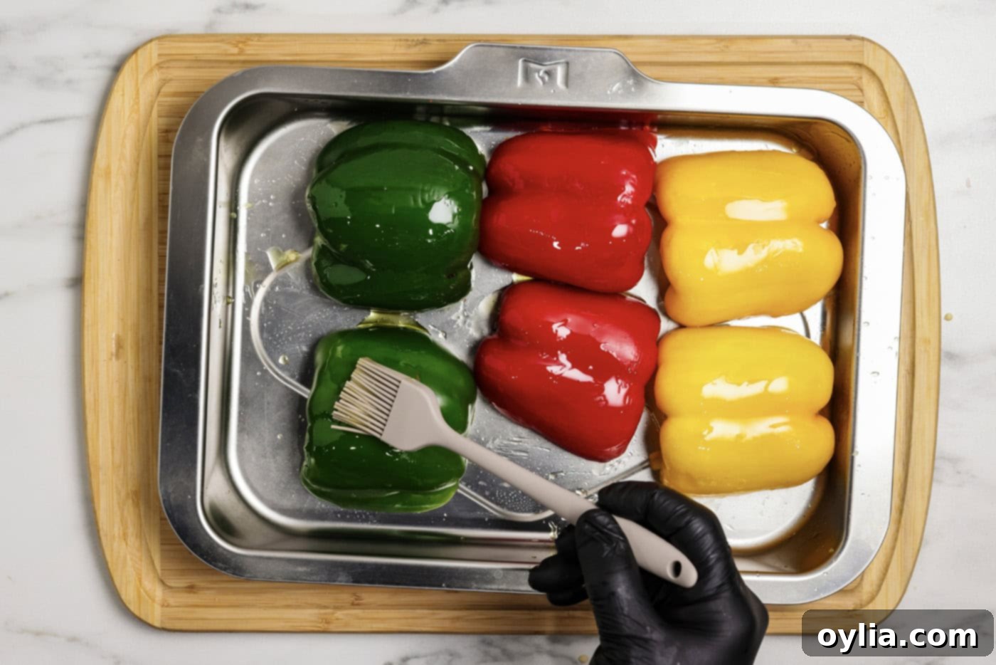 brushing bell peppers halves with olive oil on a baking sheet