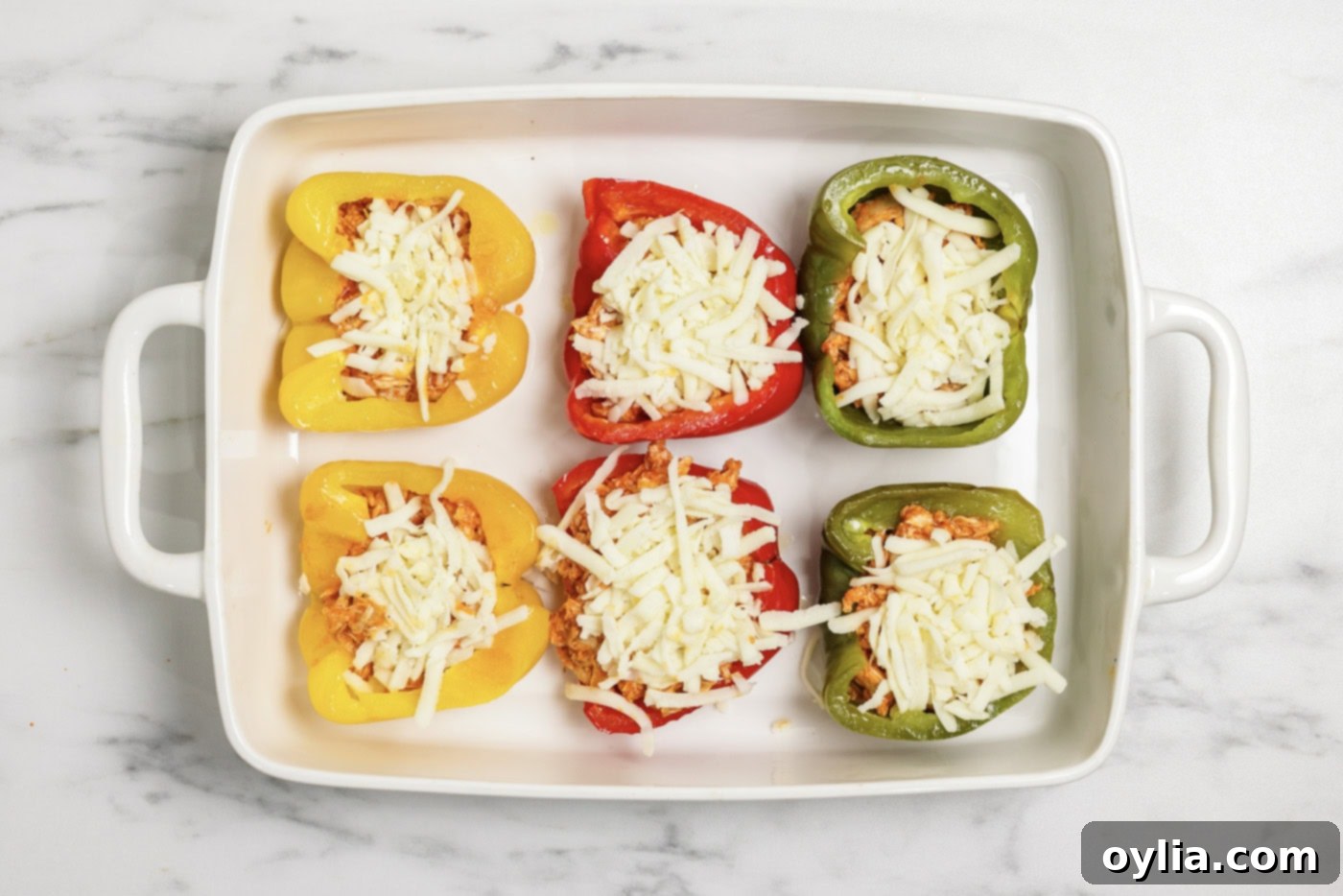 Shredded mozzarella cheese on top of buffalo chicken stuffed peppers