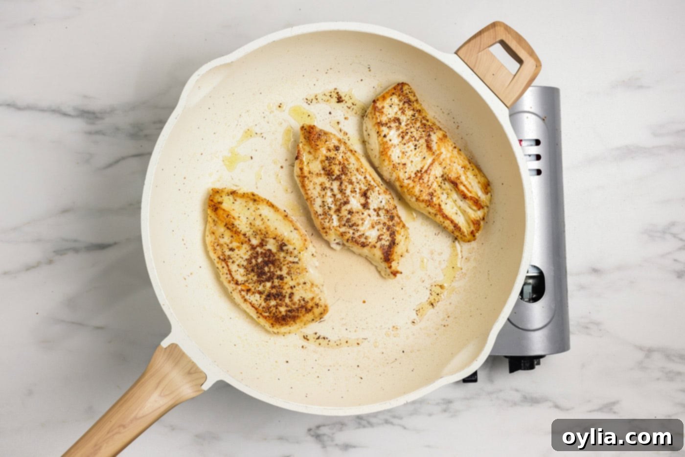 Chicken breasts cooked in a skillet with oil
