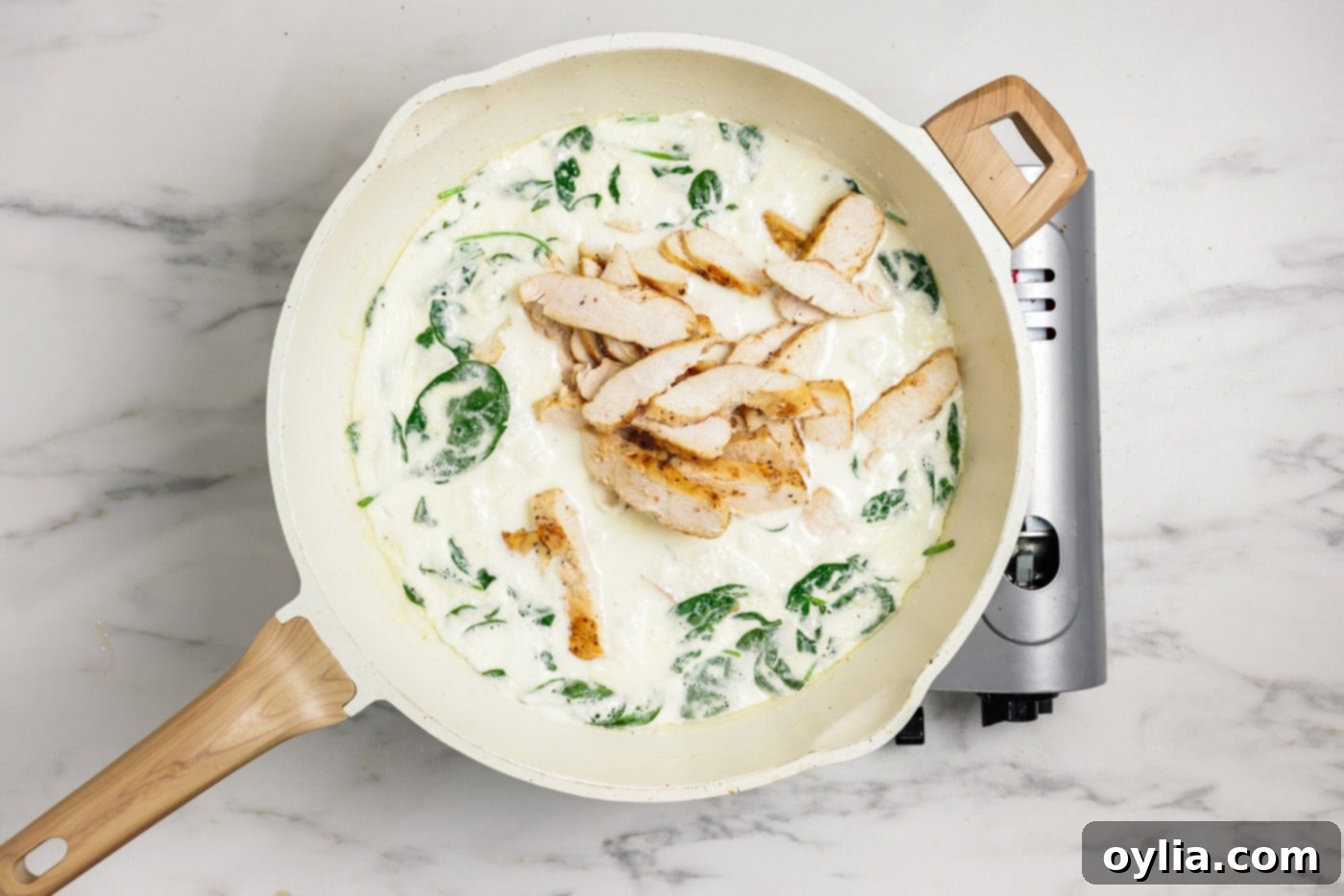 Garlic Chicken Pasta Perfection 7 spinach and sliced chicken added to garlic cream sauce in a skillet